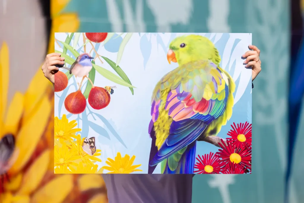A person holding up the Fine & Rare poster against the mural artwork behind them
